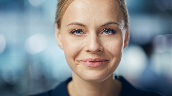 Portrait of Gorgeous Caucasian Woman with Deep Blue Eyes, Blonde Hair, Perfect Smile. Beautiful Girl Looks up at the Camera Happily. Abstract Bokeh out of Focus Background. Close-up Shot