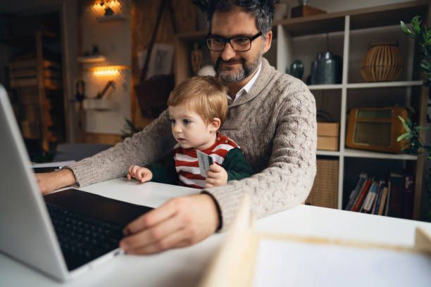 istock Modern man online shopping, while his toddler son makes him a company 1364005669