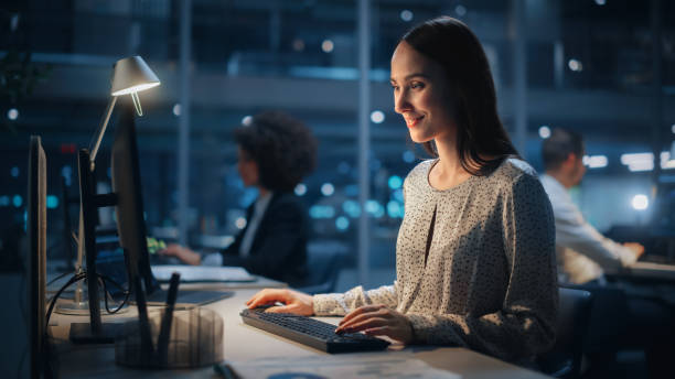 istock In Big Corporate Office at Night: Portrait of Confident Female Manager Using Computer, Businesspeople and Experts Working Around Her, Analysing Statistics, Commerce Data, Marketing Plans. 1364006920