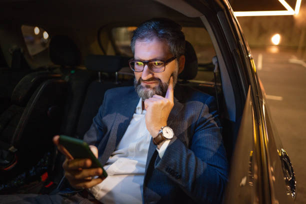 istock Confident Caucasian businessman, text messaging on the mobile phone, while sitting in the car, late at night 1364007996