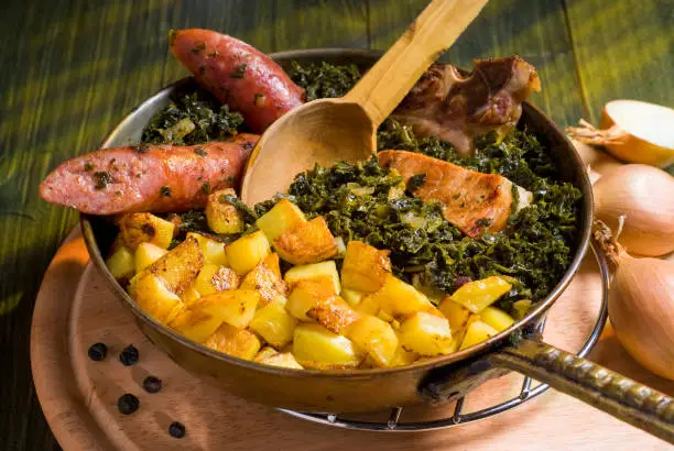 Kale pan with smokers and fried potatoes served in a serving pan.