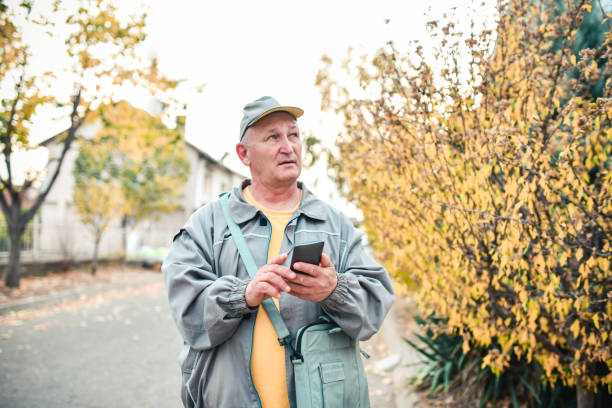 istock Senior Mailman With Smartphone Map Looking For Delivery Locations 1364010242