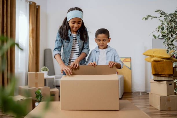 istock Siblings, girl and boy cooperate, help parents with packing things for moving, unpacking cardboard trays, joy of new apartment, excitement of children 1364010338