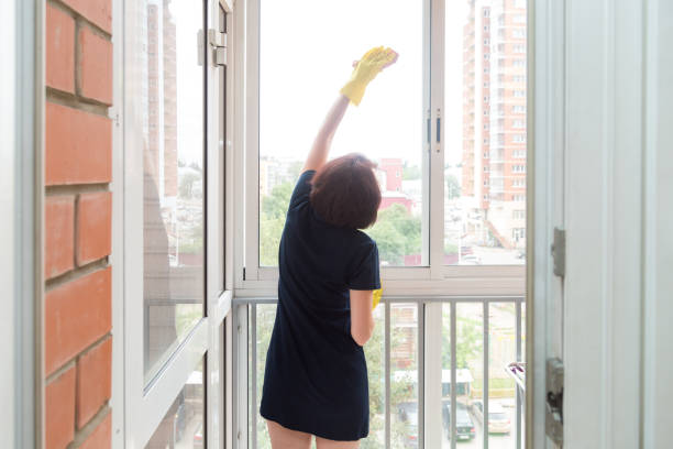 istock A small woman with difficulty washes the high windows on the balcony 1364012043