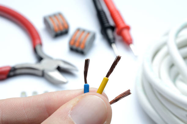 istock stripped, electrical three-core wire in hand against the background of terminal blocks and tools. close-up. 1364012372