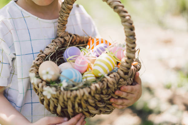 istock Easter egg hunt in spring garden. Funny boy with eggs basket and bunny ears on Easter egg hunt in sunny spring garden 1364013992