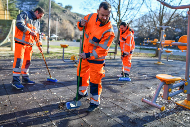 Three Sanitation Workers Cleaning Outdoor Gym From Leaves And Debris