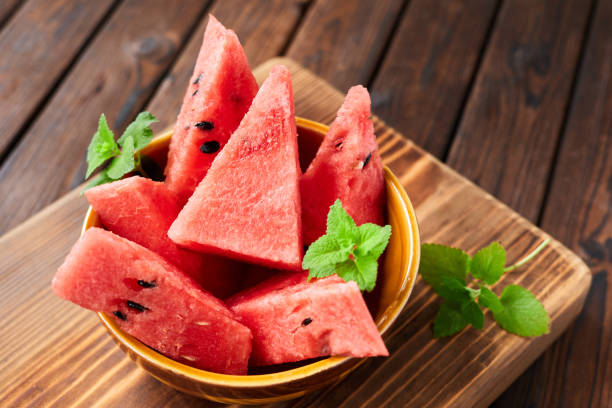 istock Sliced watermelon decorated with mint leaves on brown wooden background. Close-up, selective focus 1364016628