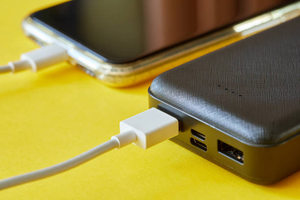 istock Power bank charges smartphone using a USB cable on yellow background. Close-up, selective focus 1364019663