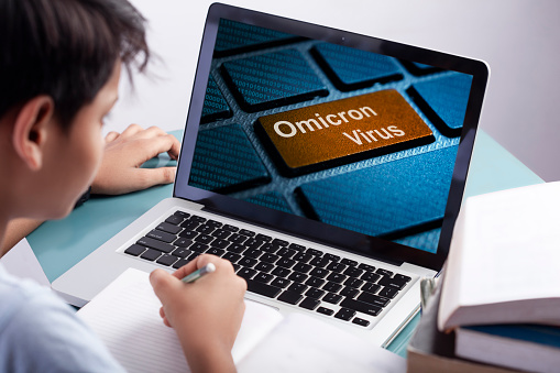 school boy watching omicron virus on laptop