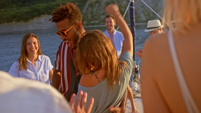 Young man and woman having fun dancing on a boat at sunset