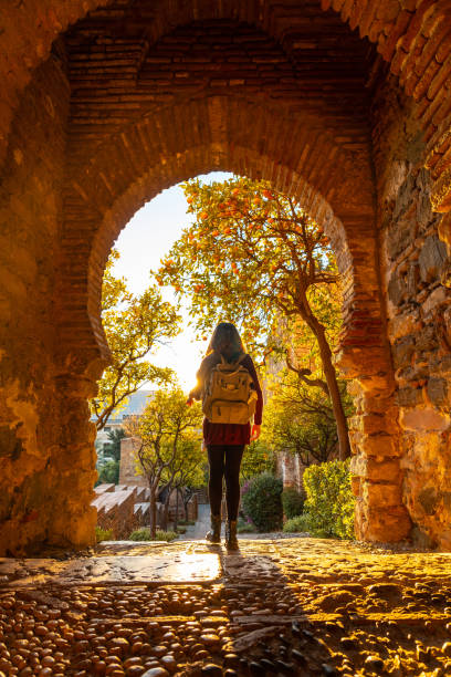 A tourist at sunset at the gate of the Alcazaba wall in the city of Malaga, Andalusia. Spain. Medieval fortress in arabic style stock photo
