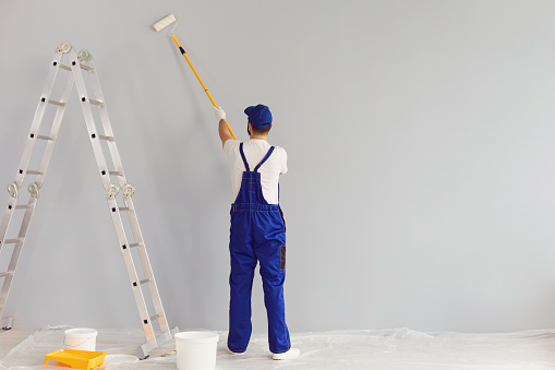 Worker painter paints a wall. Professional builder makes repairs.