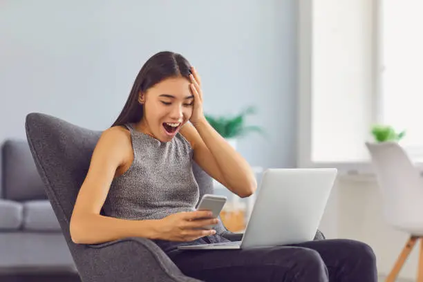 Photo of Super happy young girl receiving social media notification sitting in armchair at home