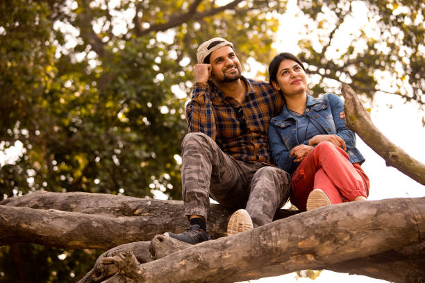 istock Young couple sitting on tree trunk and admiring nature 1364022808