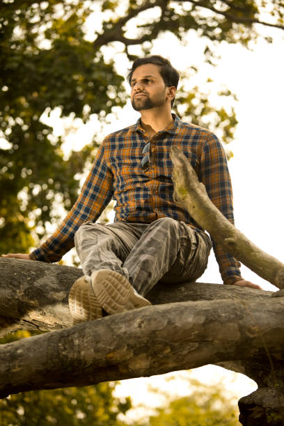 istock Man sitting on tree trunk and admiring nature 1364023878