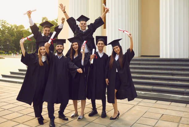 istock Cheerful university graduates posing with dimplomas in raised hands over university building 1364024044
