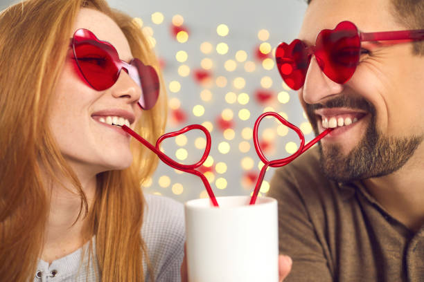 giovane uomo e donna felici innamorati che si godono un drink da una tazza in un appuntamento divertente il giorno di san valentino - flirting humor valentines day love foto e immagini stock