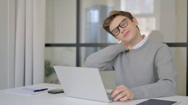 istock Young Man having Neck Pain while using Laptop in Modern Office 1364024768