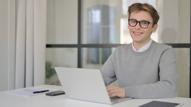 istock Young Man Shaking Head as Yes Sign while using Laptop in Modern Office 1364025025