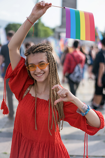 Cheerful young woman waving rainbow pride flag at the love festival