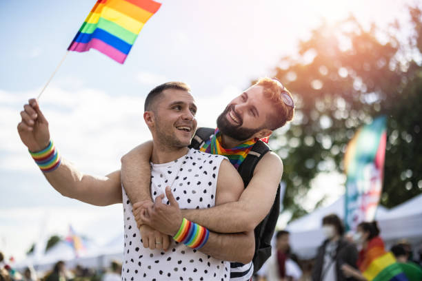 men at the lgbtq pride parade - flag rainbow gay pride flag gay man imagens e fotografias de stock