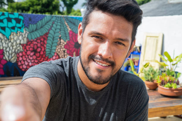 istock Smiling young adult latin man taking a selfie while looking at the camera 1364033906