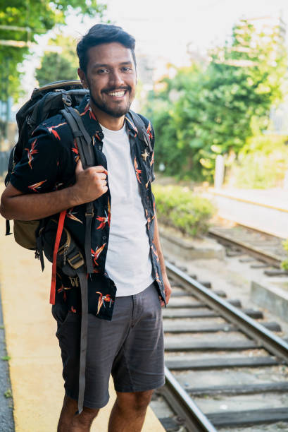 Portrait of beautiful man waiting for train on station while wearing a backpack