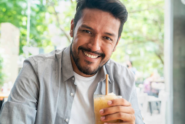 istock Smiling young latin man looking at the camera while holding cold drink 1364034121