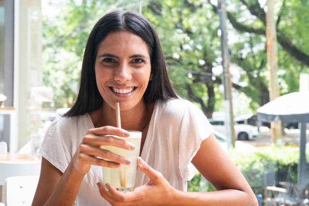 istock Beautiful latin woman holding lemonade while sitting in restaurant 1364034186