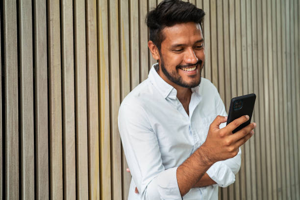 istock Groomed latin male smiling while using smartphone 1364034402