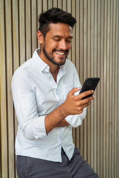 Groomed latin male smiling while using smartphone