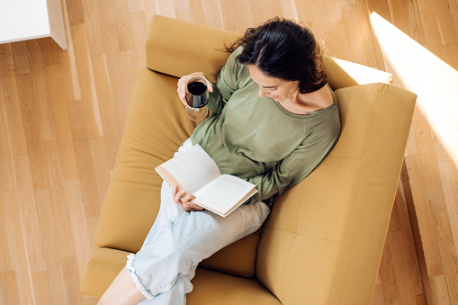 Happy woman reading and relaxing at home