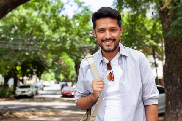 istock Young mexican man looking and smiling at the camera holding bag 1364038112