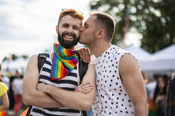 schwules paar küssen - homosexual gay man parade flag stock-fotos und bilder