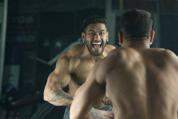 istock Muscular man flexing muscles in front of mirror 1364048089