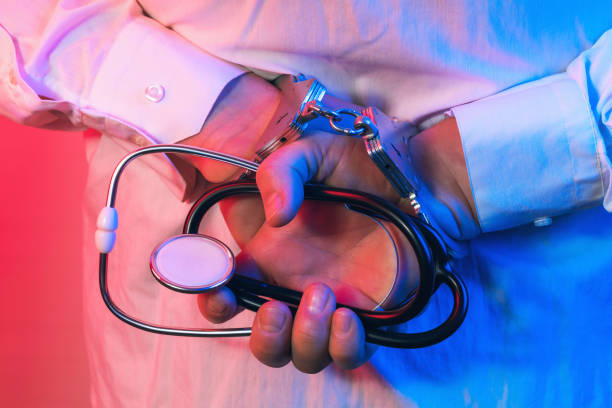 Doctor in handcuffs with a statoscope in his hands, the concept of arresting a doctor stock photo
