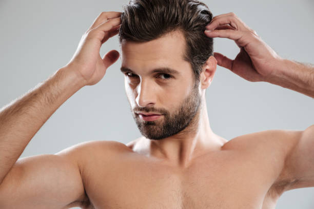 istock Charming naked bearded man posing and touching his hair 1364055180