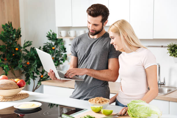 istock Happy young loving couple standing at kitchen and cooking 1364057971