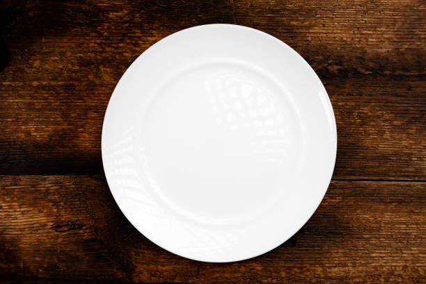 istock Empty white plate on a wooden background. Top view. 1364058884