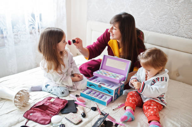 istock Mother and daughters doing makeup on the bed in the bedroom. 1364064420