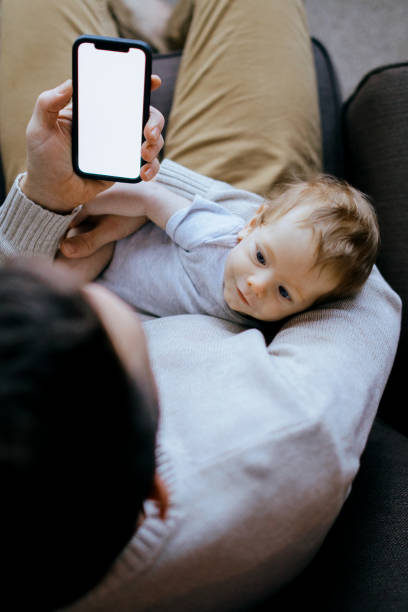 istock Father Holding Baby And Using Smart Phone 1364064421
