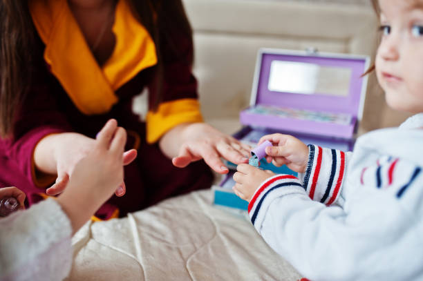 istock Mother and daughters doing manicures on the bed in the bedroom. 1364064509