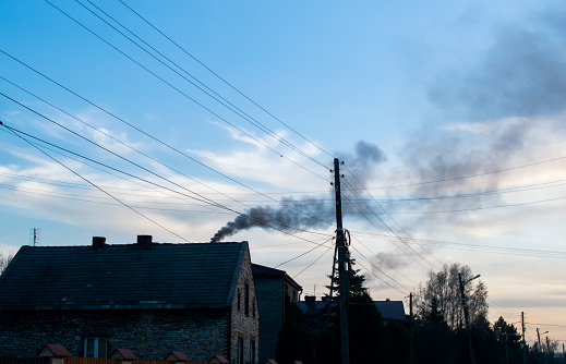 smoke from the chimney of a country house on a background of the blue sky