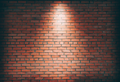Spotlight on a brick wall. background with brick wall and spotlight, copy space. stone background. Light from lamp on concrete texture . Streetlight or stage for show in exhibition or museum wallpaper