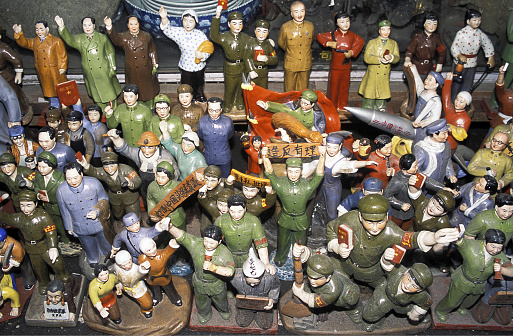 Communist Mao era figurines in political and worker costumes displayed for sale on street market stall,  Shanghai, Peoples Republic of China, East Asia. Located on the southern estuary of the Yangtze River, with the Huangpu River flowing through it, Shanghai is the most populous city in the world. Whilst Shanghai is a global center for finance, business and economics, research, education, science and technology, manufacturing, tourism, culture and transportation, and the Port of Shanghai is the world's busiest container port, signs of its heritage remain with the original Old City, or Chinese City which dates from the 11th century. Outlying villages from Shanghai, such as Wuzhen which is an historic scenic water town, part of Tongxiang, located in the north of Zhejiang Province similarly reflects a civilization dating back over 7000yrs.