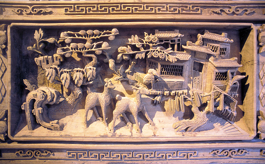 Ancient wooden wall panel carving detailing intricate rural scene ornamentation in Wuzhen, Wuzhen water town, Tongxiang near Shanghai, Peoples Republic of China, East Asia. Outlying villages from Shanghai, such as Wuzhen which is an historic scenic water town, part of Tongxiang, located in the north of Zhejiang Province similarly reflects a civilization dating back over 7000yrs. Located on the southern estuary of the Yangtze River, with the Huangpu River flowing through it, Shanghai is the most populous city in the world. Whilst Shanghai is a global center for finance, business and economics, research, education, science and technology, manufacturing, tourism, culture and transportation, and the Port of Shanghai is the world's busiest container port, signs of its heritage remain with the original Old City, or Chinese City which dates from the 11th century.