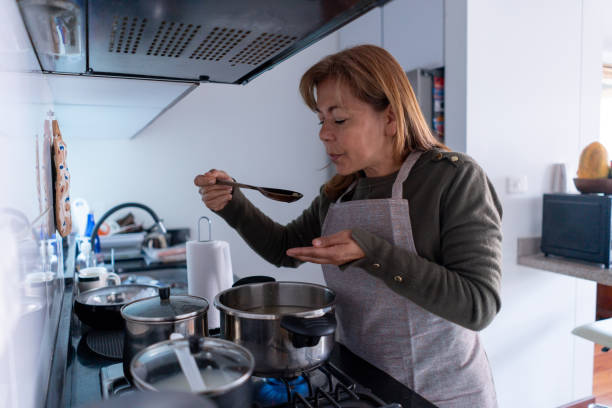 istock Mature woman at home preparing a soup tasting it while cooking 1364071227