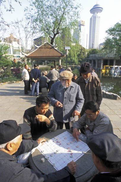пожилые мужчины играют в настольную игру в народном парке, одном из самых красивы�х городских парков города, расположенном к югу от nanjing lu road  - peoples park стоковые фото и изображения