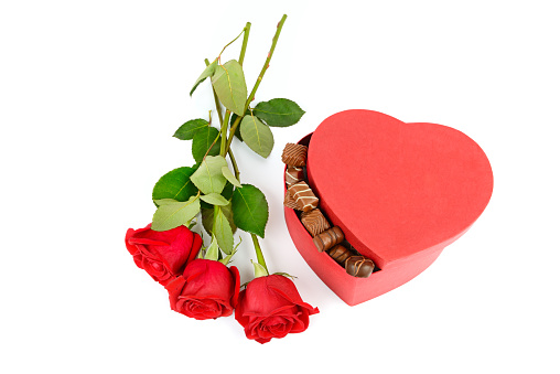 Red roses and candies in a box in the form of a heart isolated on a white background.